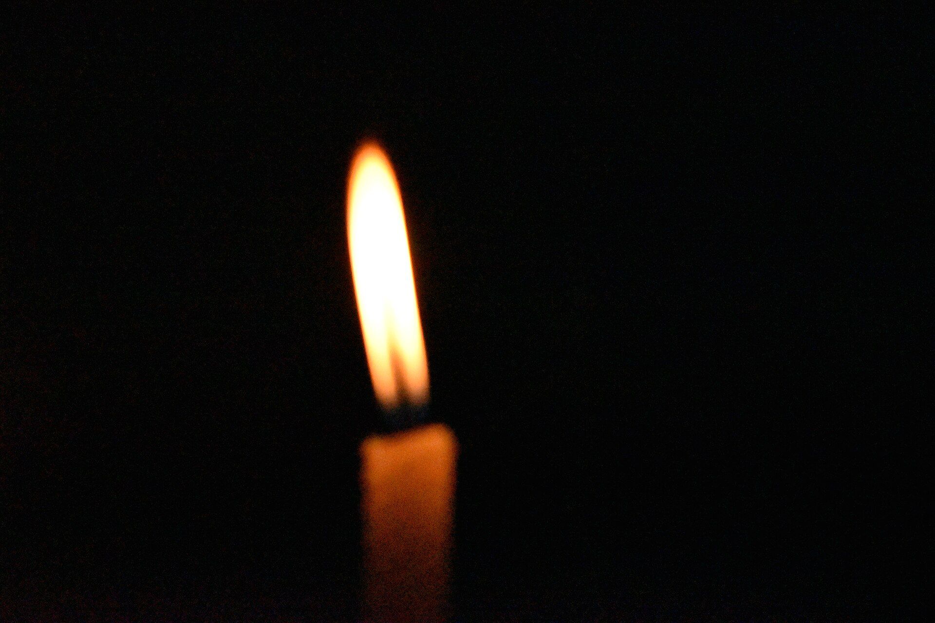 A softly lit candle against a dark background
